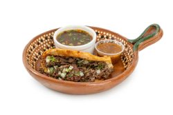 Quesabirria: A crispy, cheesy birria taco packed with tender shredded beef and grilled to perfection. Served with fresh onions and cilantro, plus a side of rich birria consomé for dipping — the perfect mix of flavor and crunch.